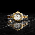 Gold and silver watch with a white face on a white background